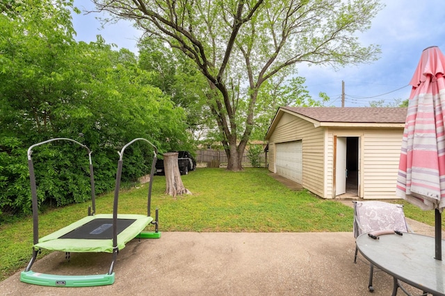 view of yard with fence, an outbuilding, a patio area, and a garage