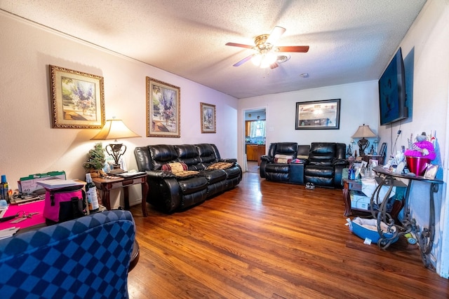 living room with a ceiling fan, a textured ceiling, and wood finished floors