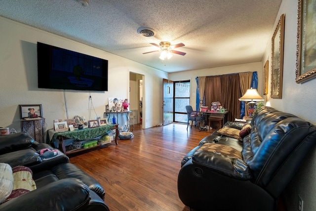 living room with a textured ceiling, ceiling fan, visible vents, and wood finished floors