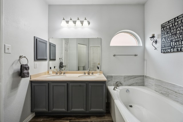 10602 Greenbriar Ln, Rowlett, TX 75089 - bathroom featuring double vanity, a sink, a bath, and wood finished floors