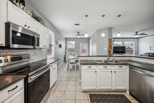 10602 Greenbriar Ln, Rowlett, TX 75089 - kitchen with dark countertops, appliances with stainless steel finishes, a sink, a ceiling fan, and decorative backsplash