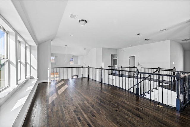 empty room featuring a notable chandelier, wood finished floors, and visible vents
