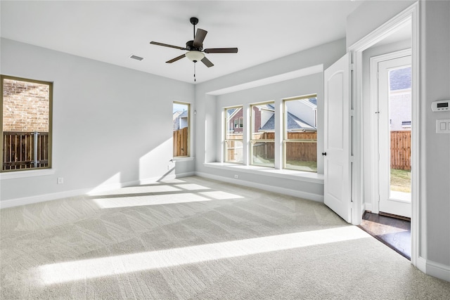 unfurnished room featuring a ceiling fan, visible vents, baseboards, carpet, and a wealth of natural light
