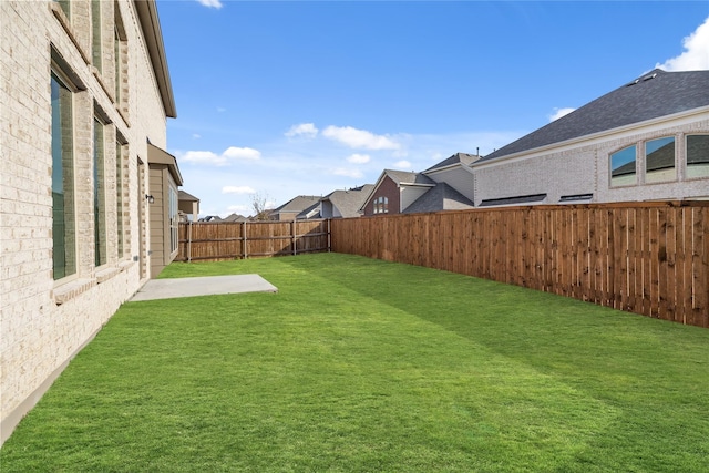 view of yard featuring a patio, a fenced backyard, and a residential view