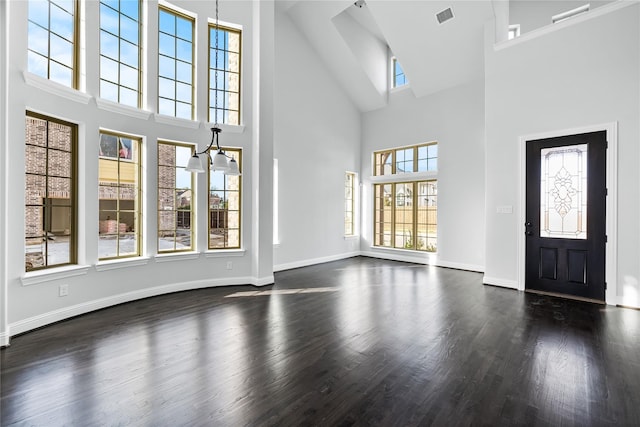 entryway featuring visible vents, dark wood-type flooring, baseboards, and a towering ceiling