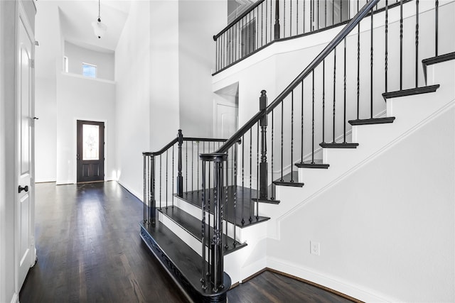 entrance foyer with stairway, baseboards, a high ceiling, and wood finished floors