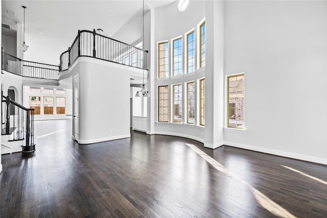 unfurnished living room featuring a wealth of natural light, wood finished floors, and stairway