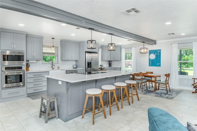 kitchen with visible vents, appliances with stainless steel finishes, gray cabinetry, a sink, and recessed lighting