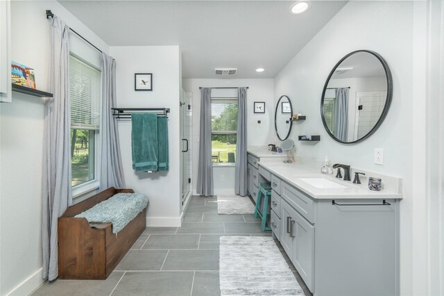 bathroom featuring vanity, baseboards, a stall shower, and visible vents