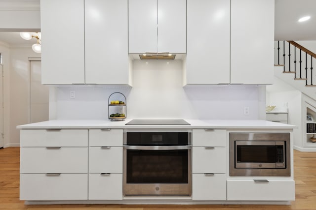 kitchen featuring modern cabinets, light wood-type flooring, light countertops, stainless steel appliances, and white cabinetry