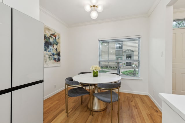 dining space with light wood-type flooring, ornamental molding, and baseboards