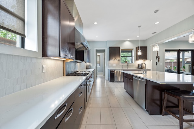 kitchen with dark brown cabinets, light countertops, a sink, backsplash, and stainless steel appliances