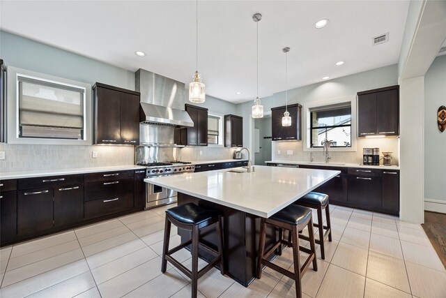 kitchen featuring a kitchen breakfast bar, light countertops, wall chimney exhaust hood, a sink, and double oven range