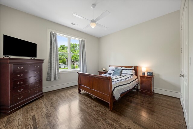 bedroom with baseboards, a baseboard heating unit, wood finished floors, and visible vents