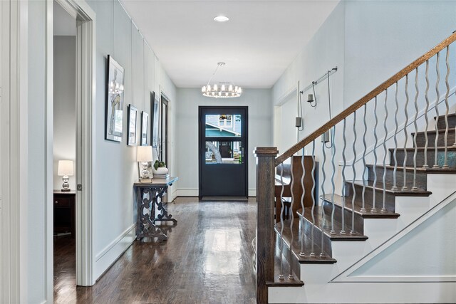 foyer entrance with baseboards, stairs, wood finished floors, and a notable chandelier