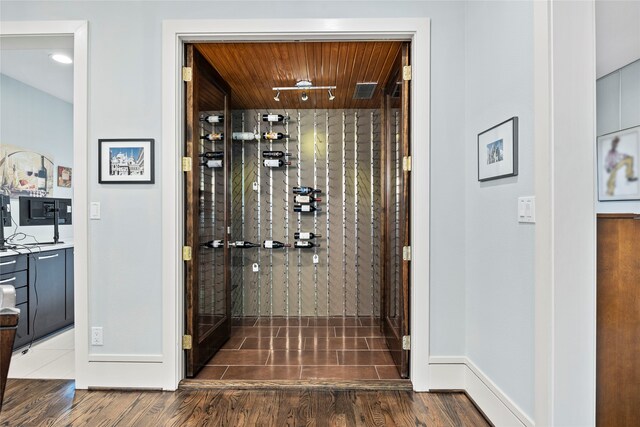 wine area with baseboards, wood ceiling, and wood finished floors