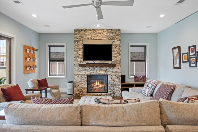 living area featuring a stone fireplace, recessed lighting, ceiling fan, and visible vents