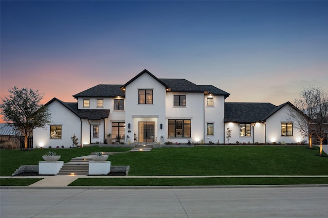 modern farmhouse style home with stucco siding and a yard