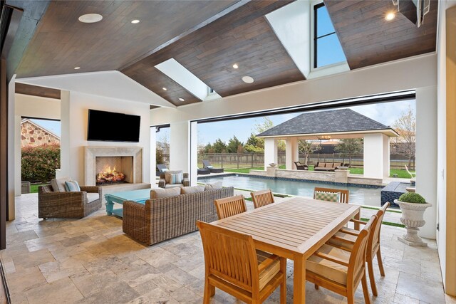 view of patio with a gazebo, fence, an outdoor pool, and an outdoor living space with a fireplace