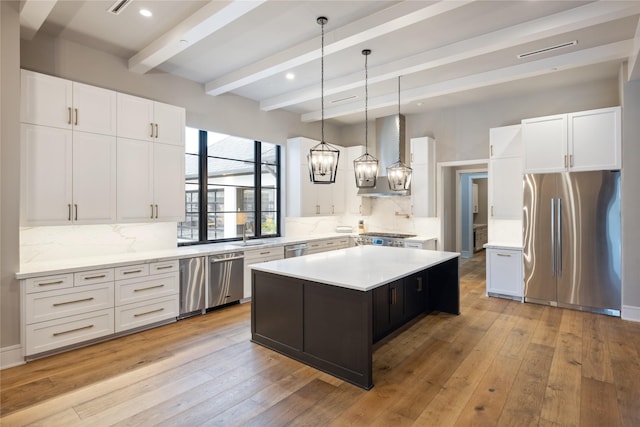 kitchen with decorative backsplash, a center island, beamed ceiling, stainless steel appliances, and wall chimney exhaust hood