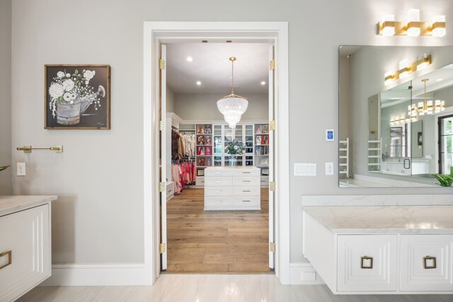 bathroom with vanity, recessed lighting, baseboards, and a chandelier