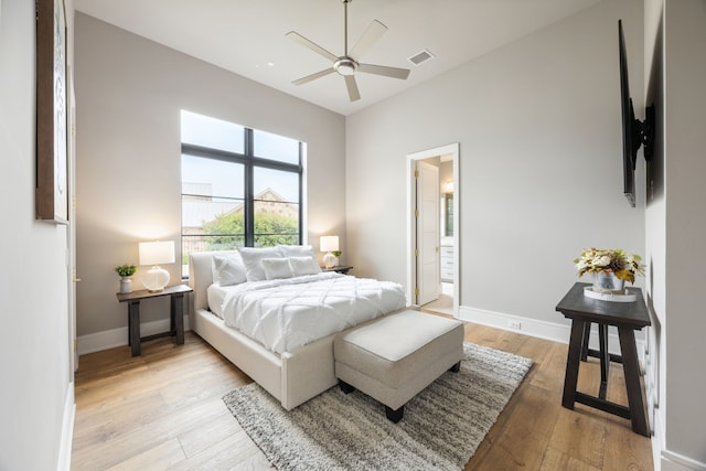 bedroom with ceiling fan, visible vents, baseboards, ensuite bathroom, and light wood-style flooring