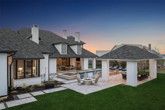 rear view of house featuring an outdoor living space with a fire pit, a patio, a chimney, a gazebo, and a yard