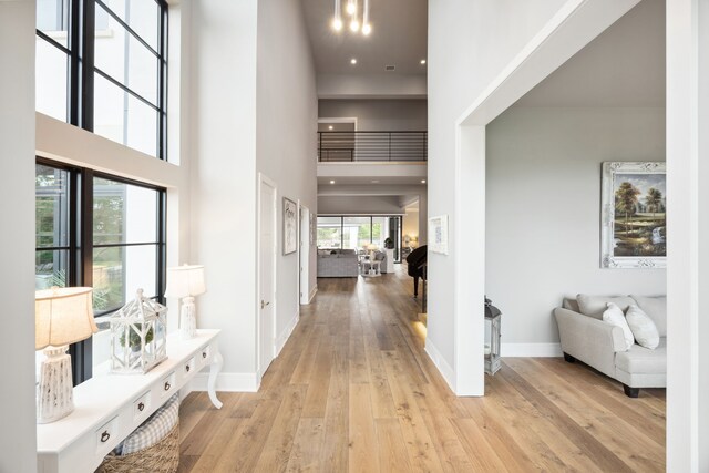 foyer entrance featuring baseboards, recessed lighting, light wood-style floors, and a high ceiling