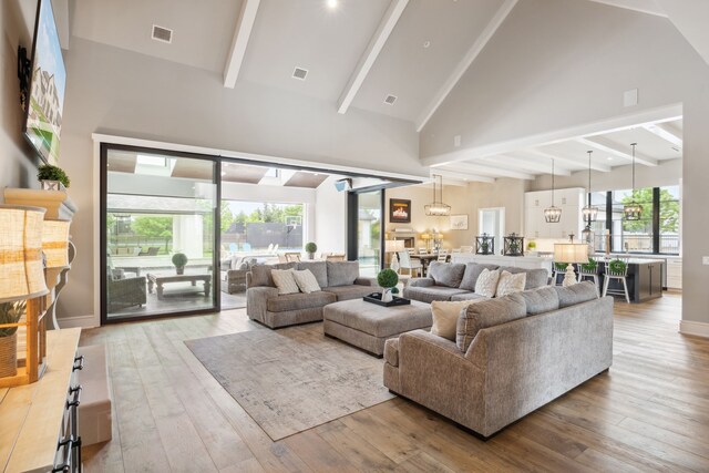 living room with visible vents, beam ceiling, high vaulted ceiling, baseboards, and wood-type flooring