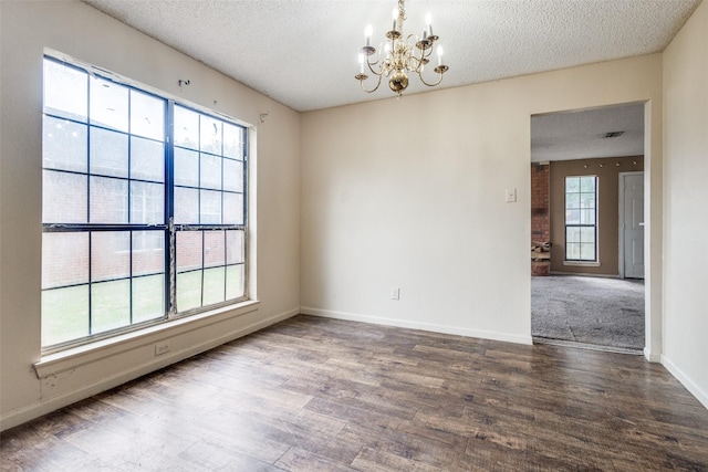 empty room with baseboards, a textured ceiling, an inviting chandelier, and wood finished floors