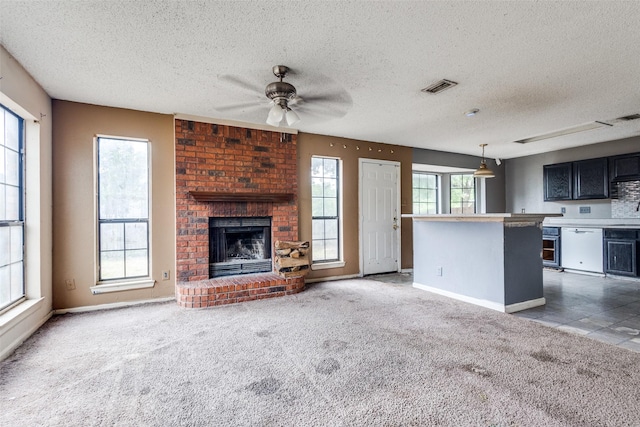 unfurnished living room featuring ceiling fan, a fireplace, a textured ceiling, and visible vents