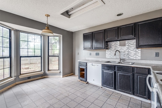 kitchen with a sink, white dishwasher, a textured ceiling, and light countertops