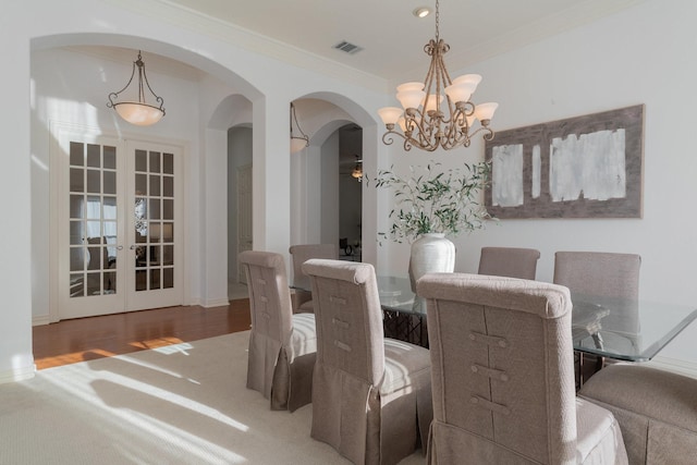 dining space featuring visible vents, ornamental molding, a chandelier, french doors, and arched walkways