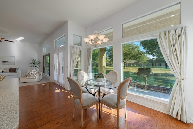 dining space with wood finished floors and ceiling fan with notable chandelier