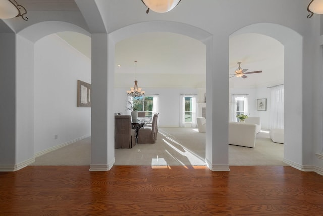 hall with arched walkways, light wood finished floors, and a chandelier