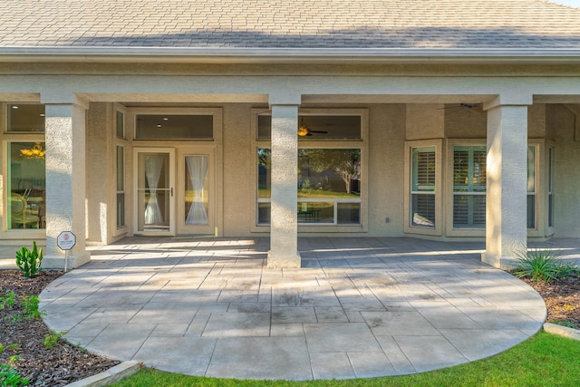 entrance to property featuring a patio area and roof with shingles