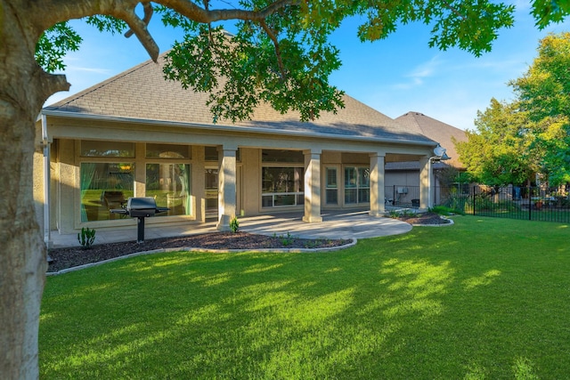 back of house with a lawn, a patio area, fence, and roof with shingles