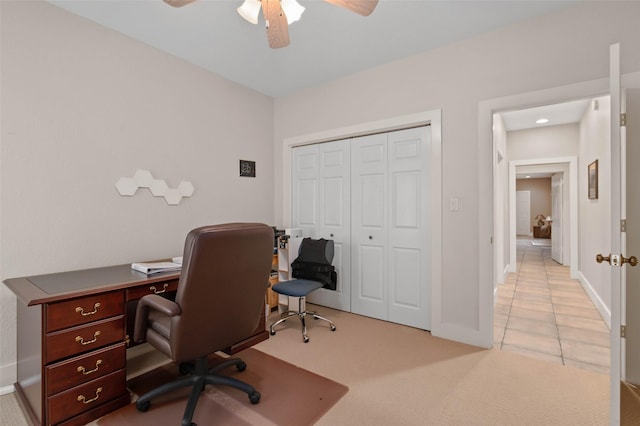 carpeted office space with ceiling fan and baseboards