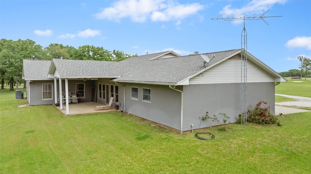 rear view of property with a yard, cooling unit, a shingled roof, and a patio area