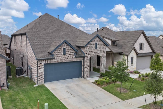 french provincial home with brick siding, an attached garage, driveway, and a front lawn