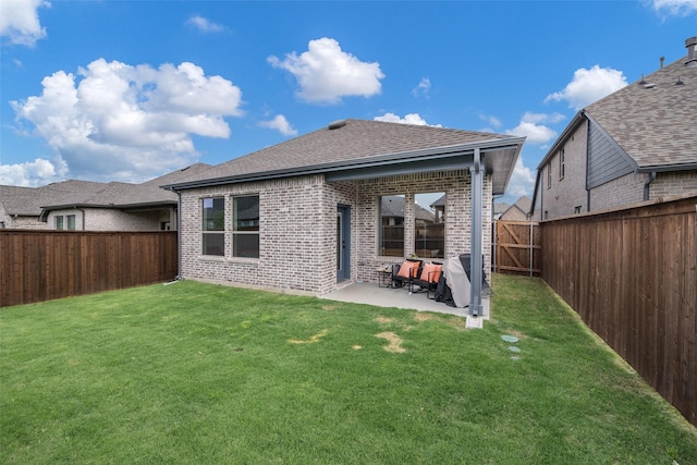rear view of property with a fenced backyard, brick siding, a shingled roof, a patio area, and a lawn
