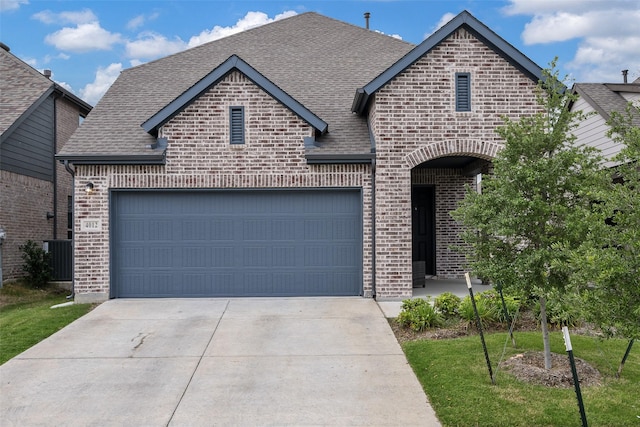 french provincial home with a garage, a shingled roof, driveway, and brick siding