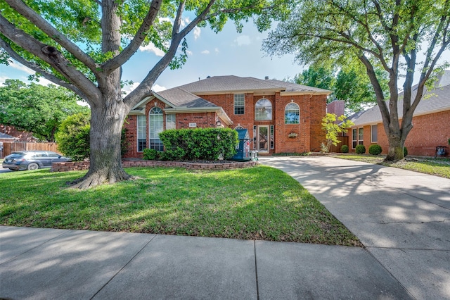view of front of home featuring brick siding, driveway, and a front yard