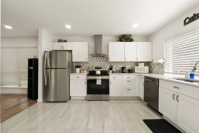 kitchen featuring a sink, white cabinets, stainless steel appliances, and wall chimney exhaust hood