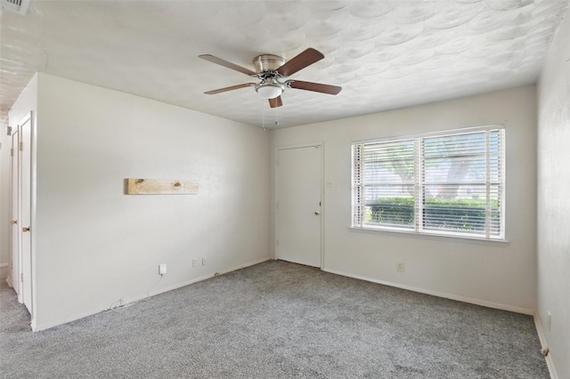 carpeted empty room with ceiling fan, visible vents, and baseboards