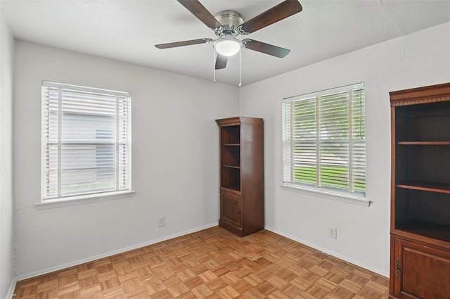 spare room with a ceiling fan and baseboards