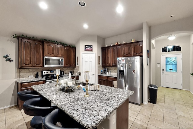 11800 Bexley Dr, Burleson, TX 76028 - kitchen featuring appliances with stainless steel finishes, arched walkways, light tile patterned flooring, backsplash, and dark brown cabinetry