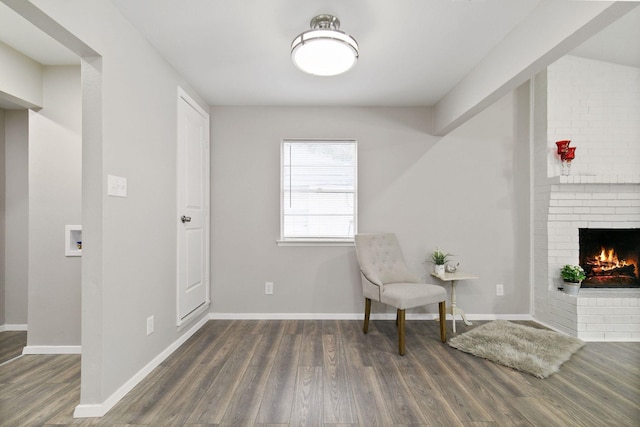 living area with baseboards, wood finished floors, and a fireplace