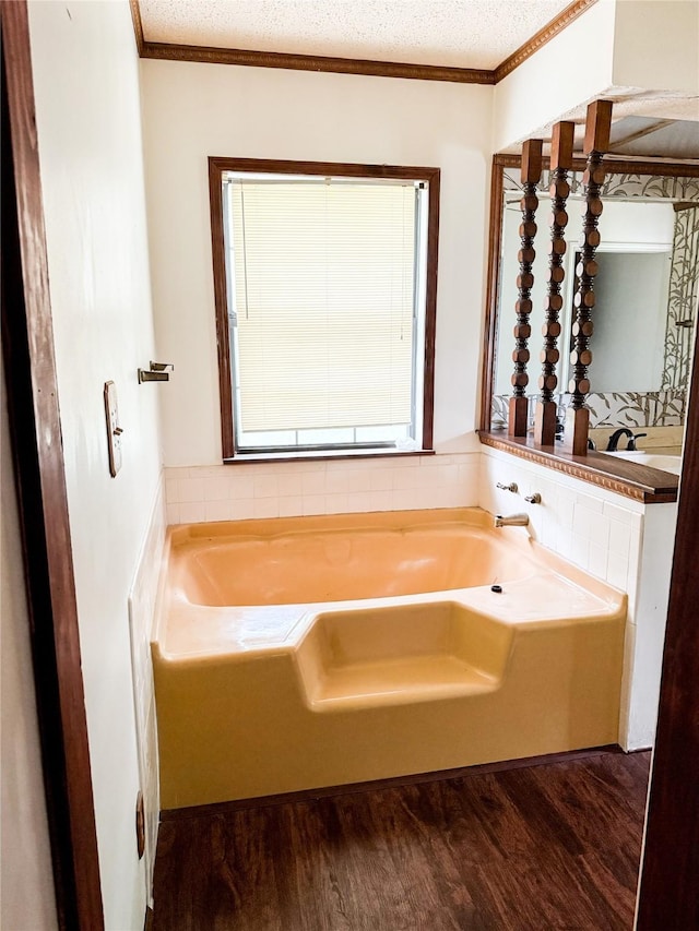bathroom featuring crown molding, a textured ceiling, wood finished floors, and a garden tub