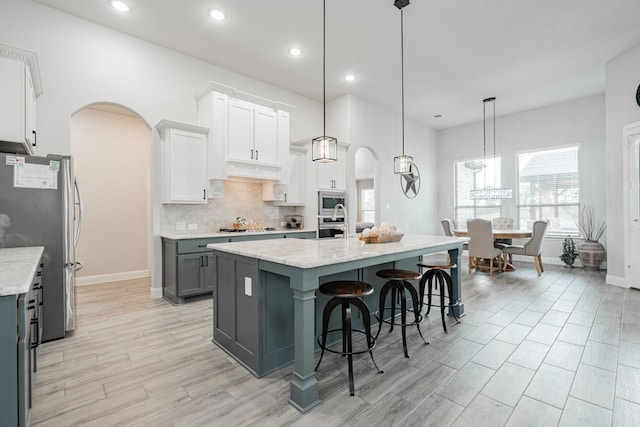 426 Norbury Dr, Rockwall, TX 75032 - kitchen featuring backsplash, appliances with stainless steel finishes, arched walkways, baseboards, and light wood finished floors